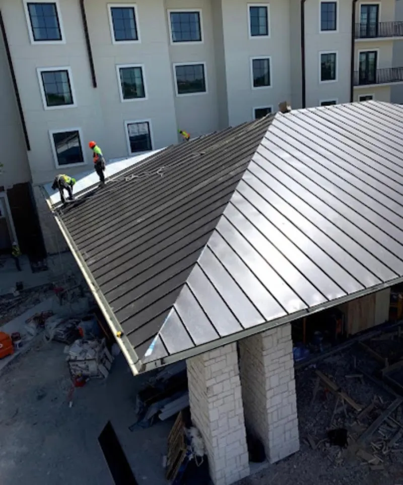 Crew installing standing seam metal roof panels on a commercial project in Upper Milford